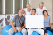 Beschreibung: Senioren halten Schild im Fitnesscenter